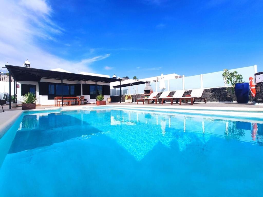 a large swimming pool with chairs and a building at Villa 21 in Puerto del Carmen