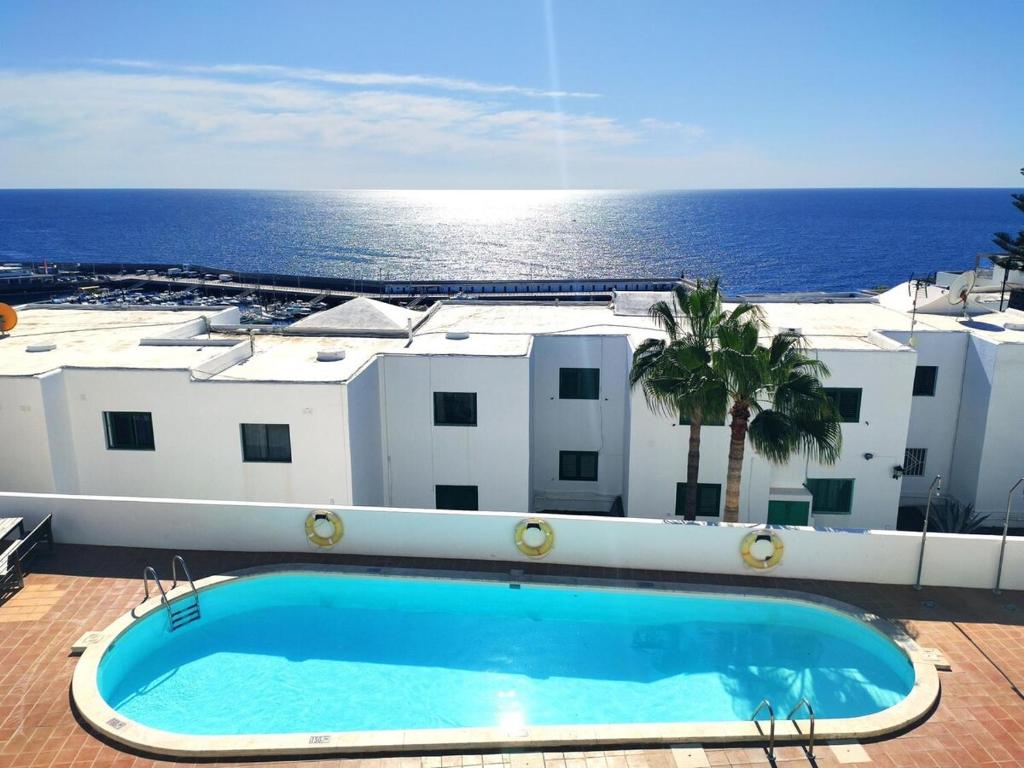 a swimming pool in front of a building with the ocean at Casa Zoe in Puerto del Carmen