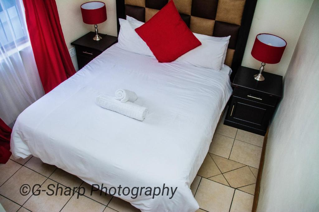 a bedroom with a white bed with two red pillows at @431 Rupert Street in Pretoria