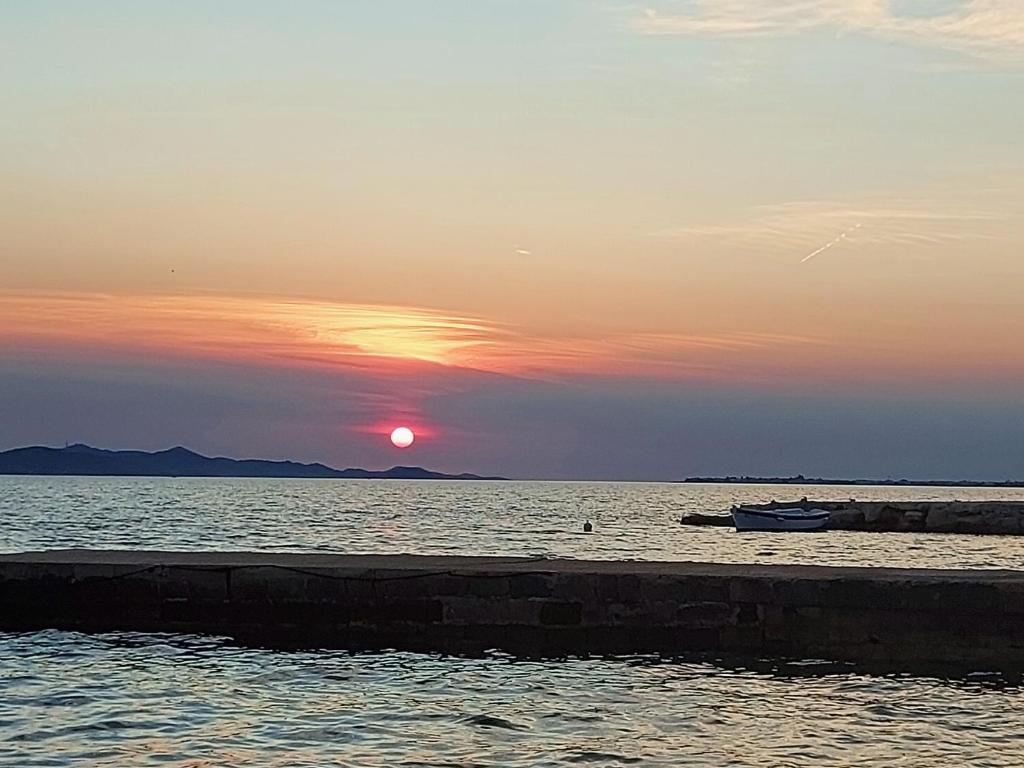 un tramonto su un corpo d'acqua con una barca di Apartmani Sunce a Sveti Petar