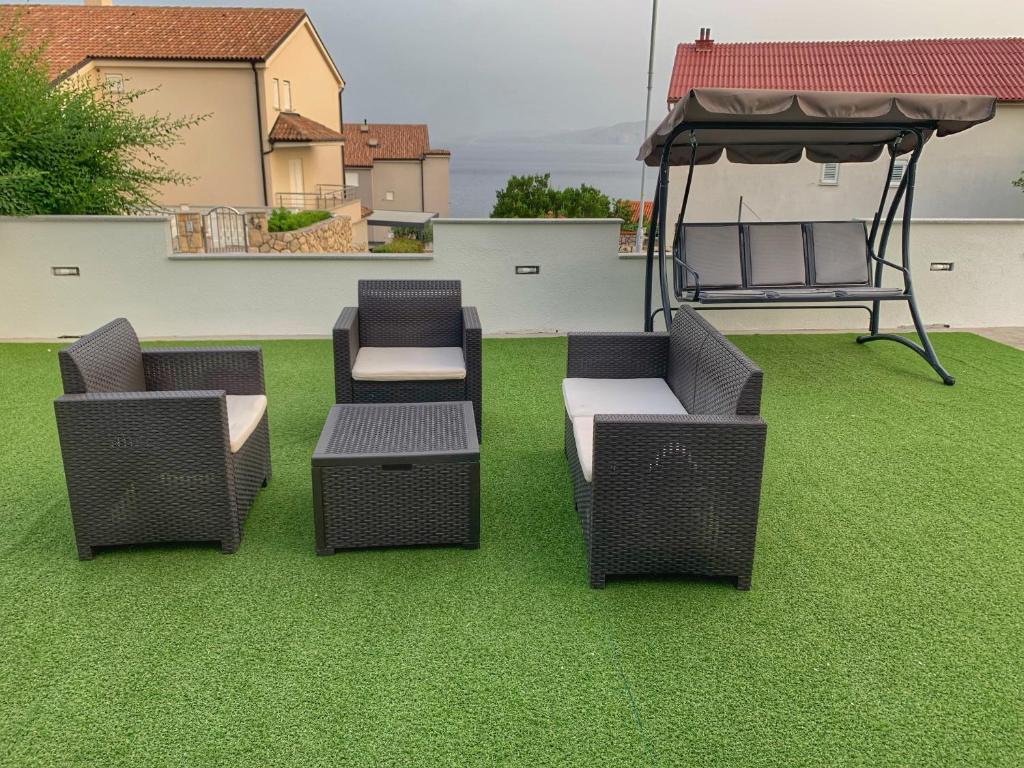 three wicker chairs and a table on a lawn at Apartment Lea Mataija in Novi Vinodolski