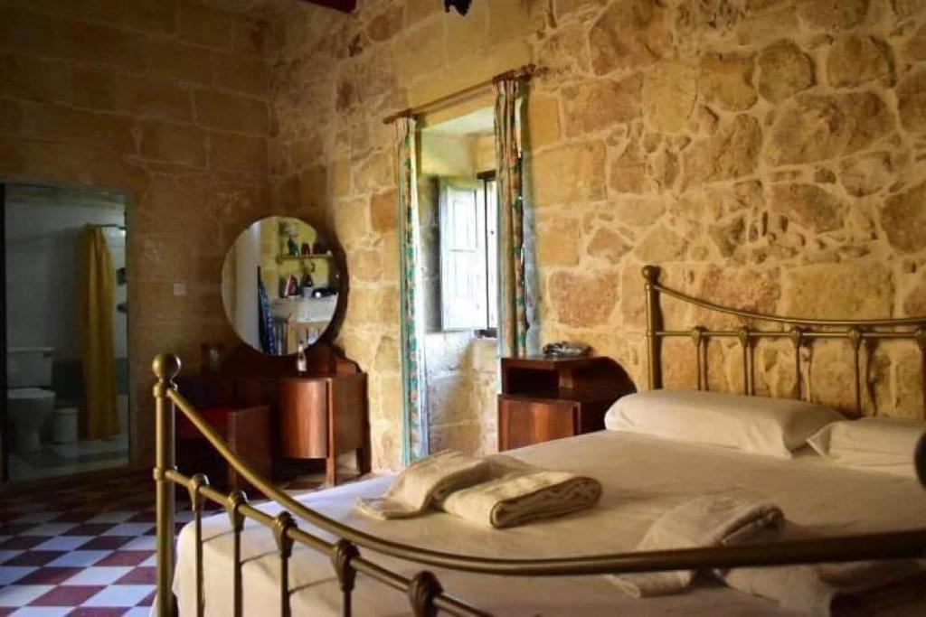a bedroom with a bed and a stone wall at Ta' Salvu u Marija in Munxar