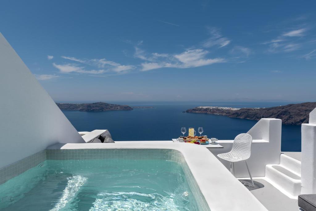 una piscina al lado de una casa con el océano en Kasimatis by La Perla - Adults Only, en Imerovigli