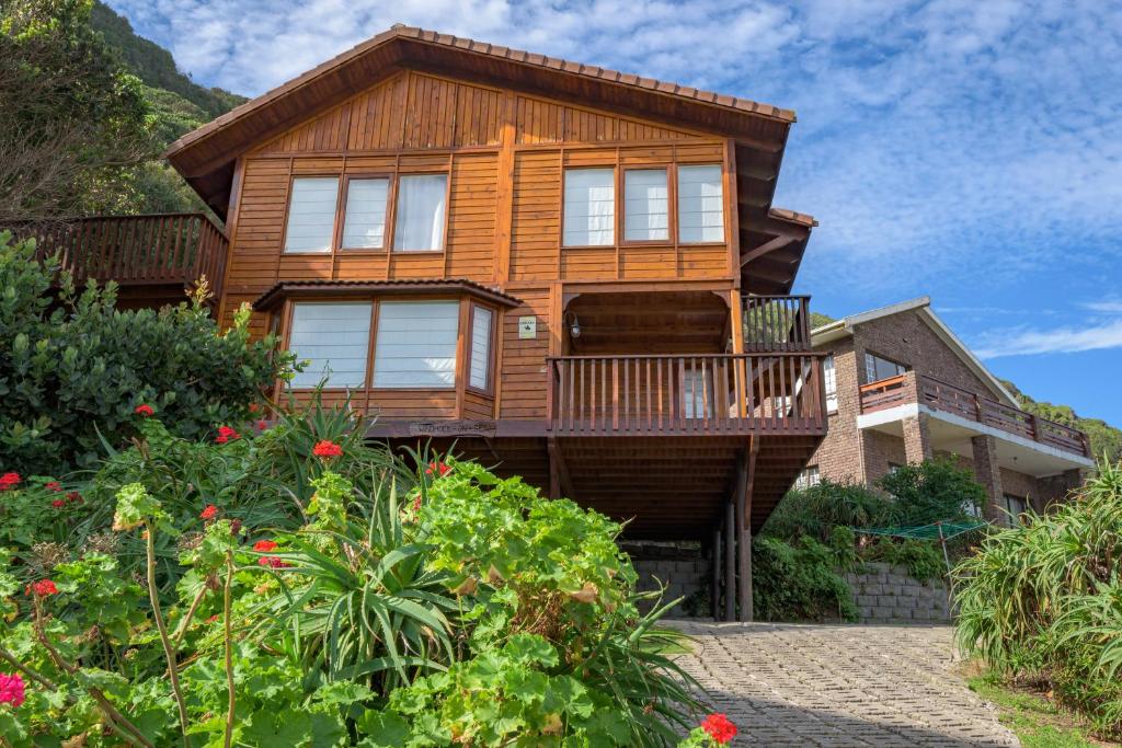 a wooden house with a balcony and flowers at Windhoek on Sea in Eersterivierstrand