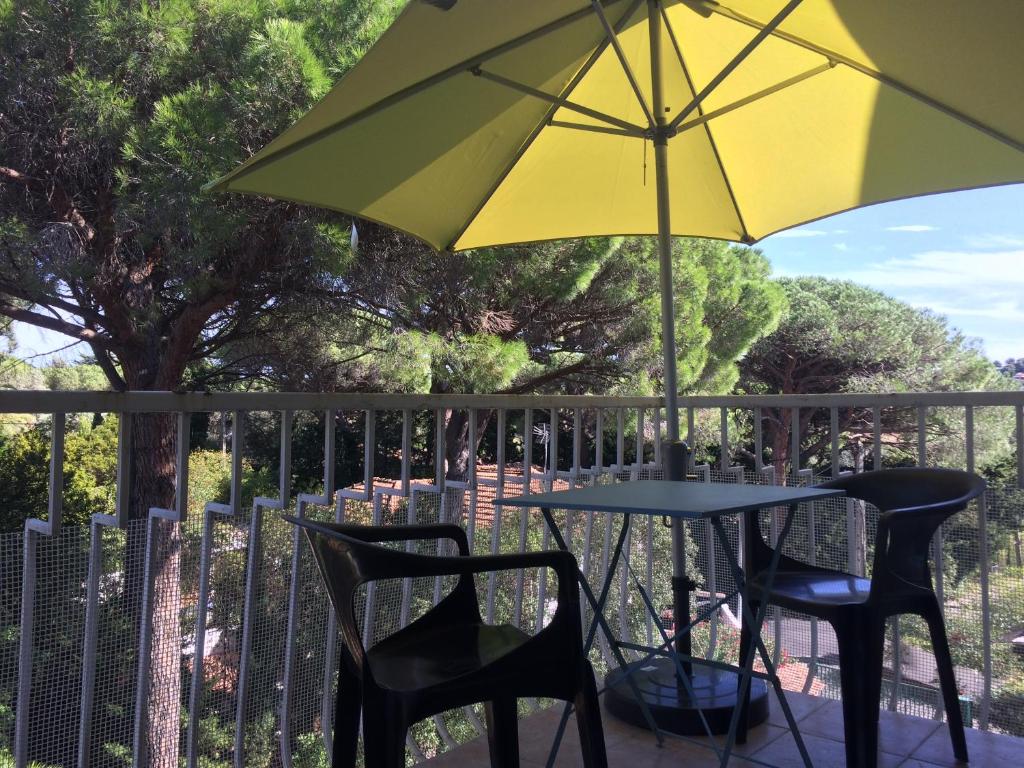 une table et des chaises avec un parasol sur une clôture dans l'établissement studio cavalaire/mer proche de ST tropez, à Cavalaire-sur-Mer