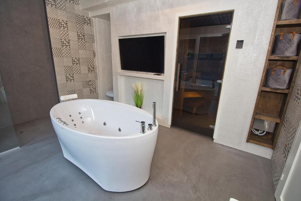 a white bath tub in a bathroom with a television at Casa Monkey Pärnu with sauna and terrace in Pärnu