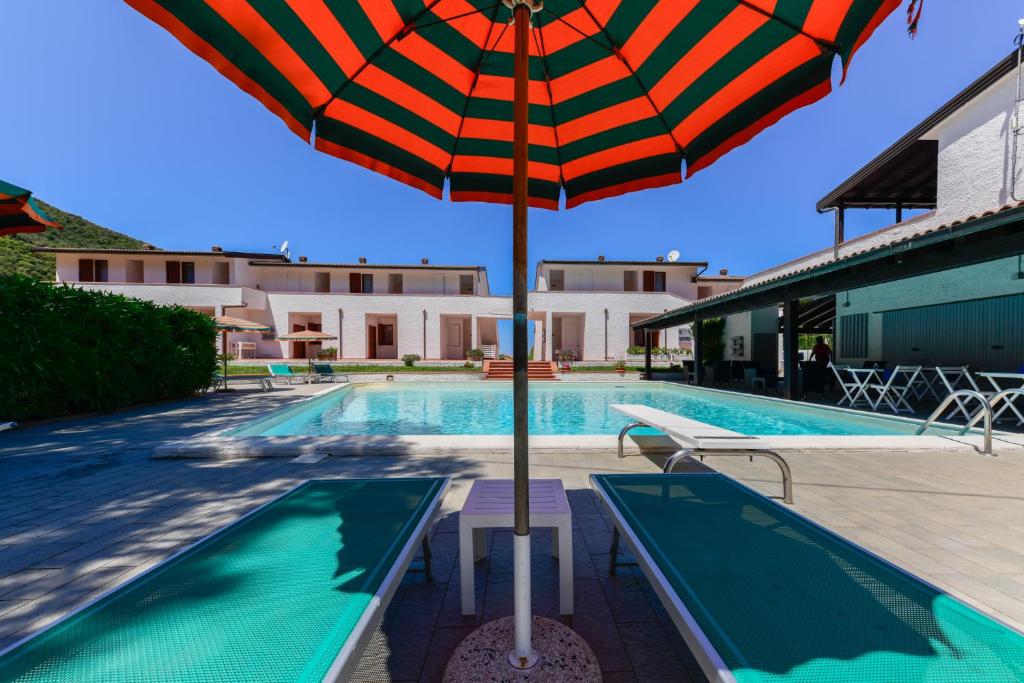 an umbrella sitting next to a swimming pool at Elba Island Resort Pool & Tennis in Nisporto