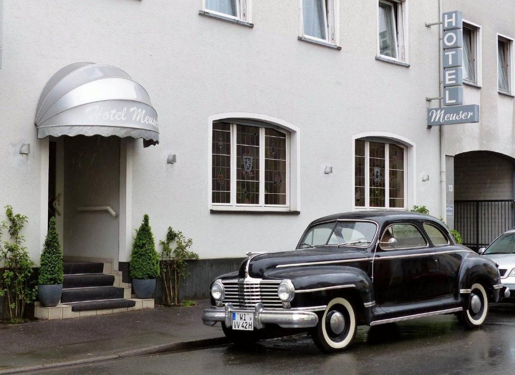 une vieille voiture noire garée devant un bâtiment dans l'établissement Hotel Meuser, à Wiesbaden