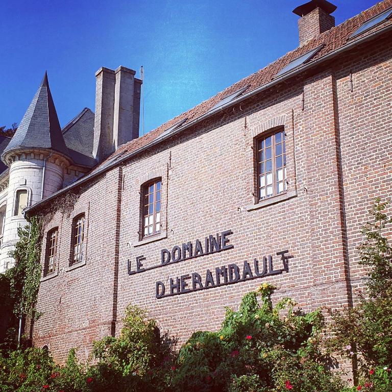 a brick building with a sign on it with a castle at Le Domaine d'Hérambault in Montcavrel