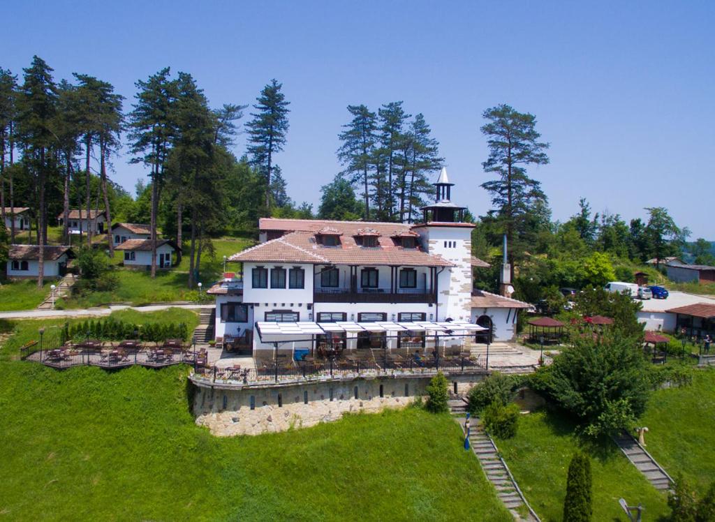 a large white house with a tower on top of a field at Complex Brashlyan in Tryavna
