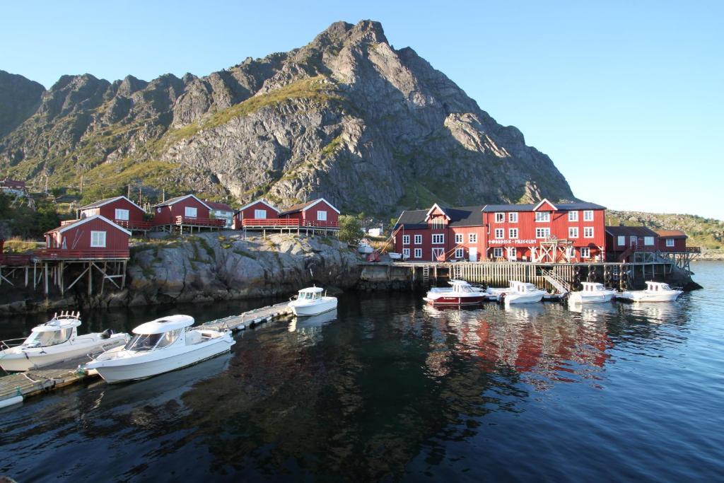 a group of boats docked in a harbor with a mountain at Å-Hamna Rorbuer in Å