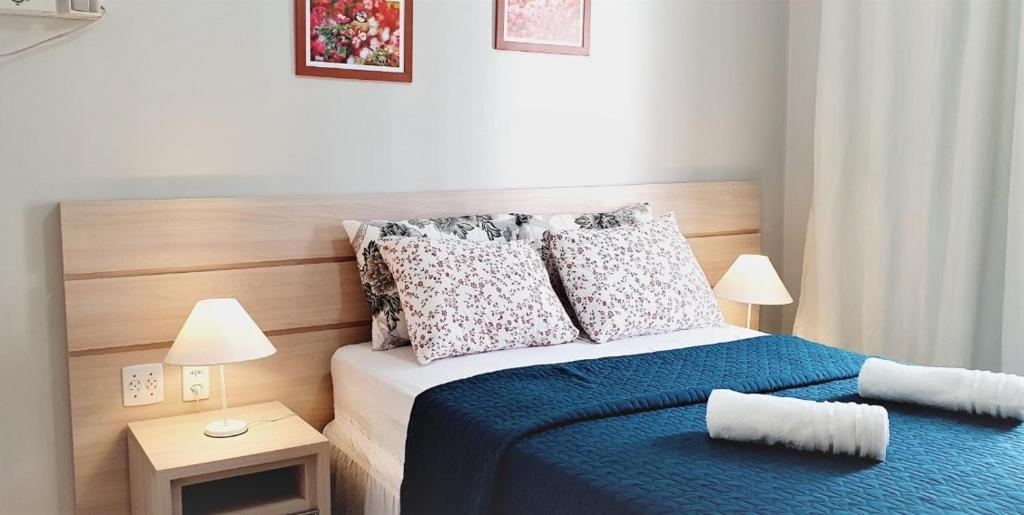 um pequeno quarto com uma cama com lençóis e almofadas azuis em Luxuria Apartamento Palazzo di Italia em Goiânia
