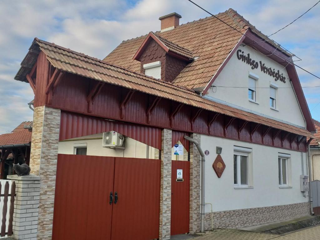 una casa con un edificio rojo y blanco en Ginkgo Apartman en Demjén