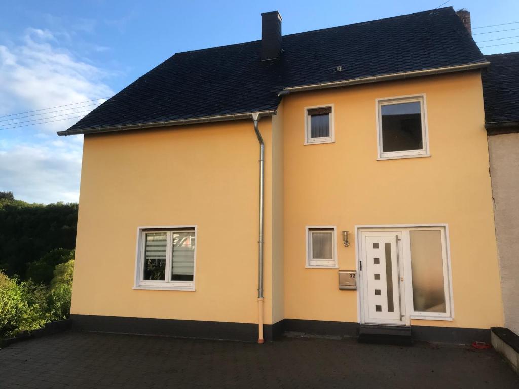 ein gelbes Haus mit weißer Tür in der Unterkunft Ferienwohnung in Maring-Noviand in Maring-Noviand