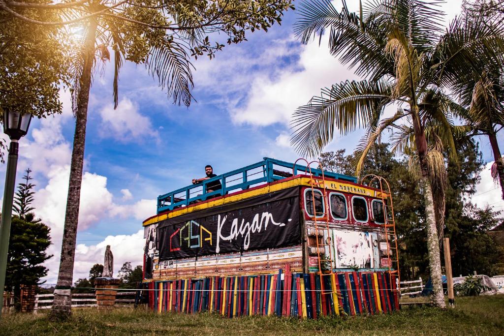 un hombre está de pie en la parte superior de un viejo autobús en Casa Kayam Hostal y Residencia Artística en Guatapé