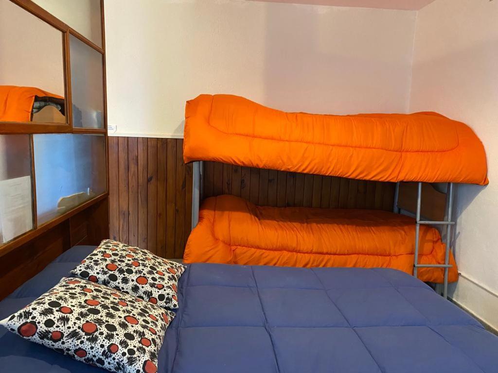 1 dormitorio con 2 literas y sábanas de color naranja en El Canto de la Ballena Loft en Puerto Pirámides