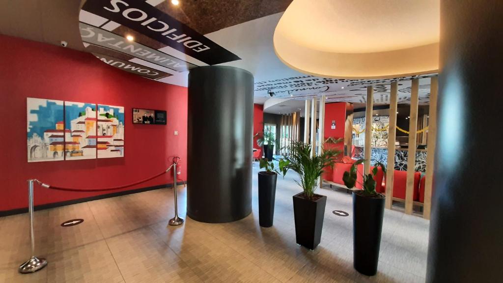 um átrio com vasos de plantas e paredes vermelhas em Hotel ibis Lisboa Jose Malhoa em Lisboa