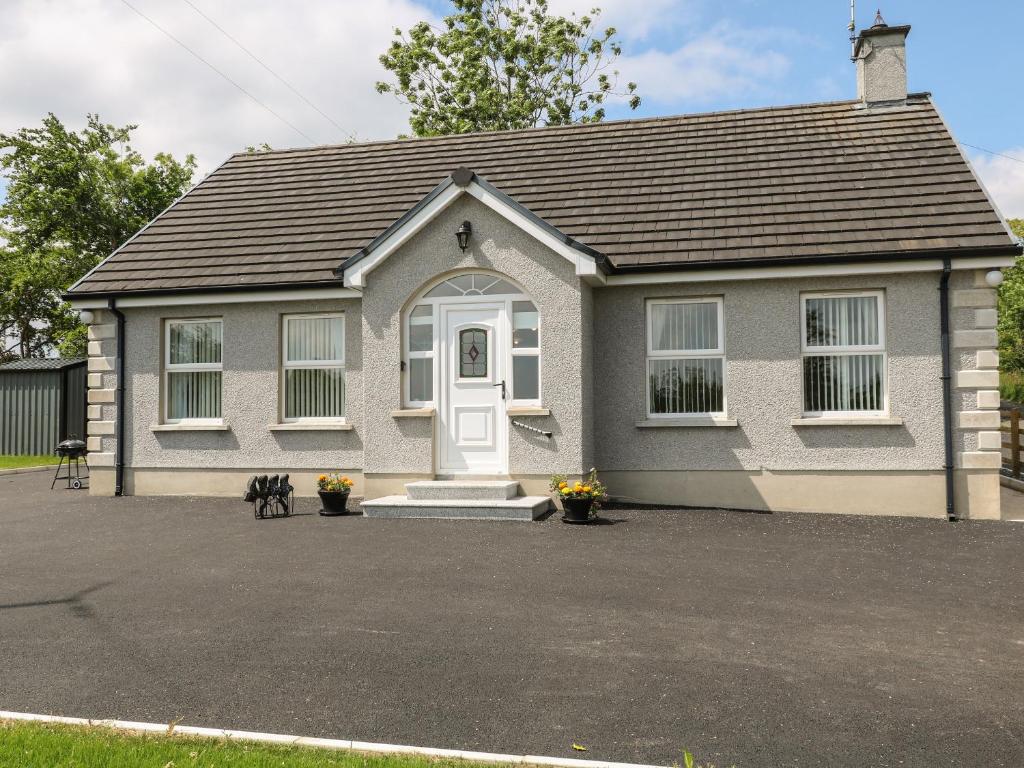 a small house with a white door on a driveway at Slieve Gallion Cottage in Magherafelt