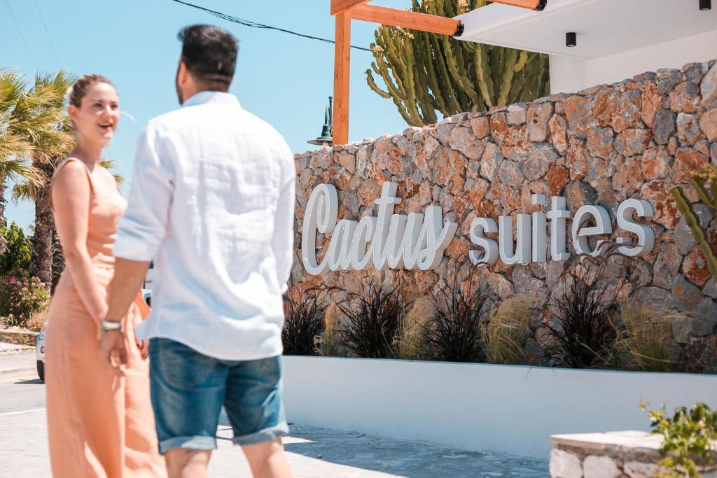 Un uomo e una donna in piedi davanti a un cartello dell'hotel di cactus suites a Faliraki