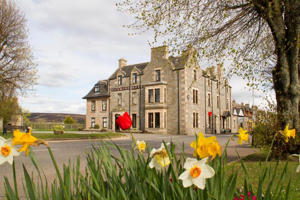 uma casa velha com flores em frente em Richmond Arms Hotel em Tomintoul