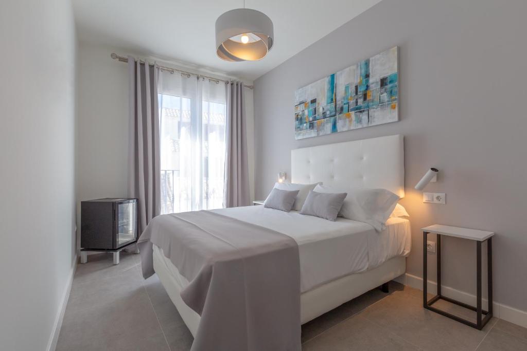 een witte slaapkamer met een groot bed en een televisie bij The Old Town Boutique Hotel - Adults Only in Estepona