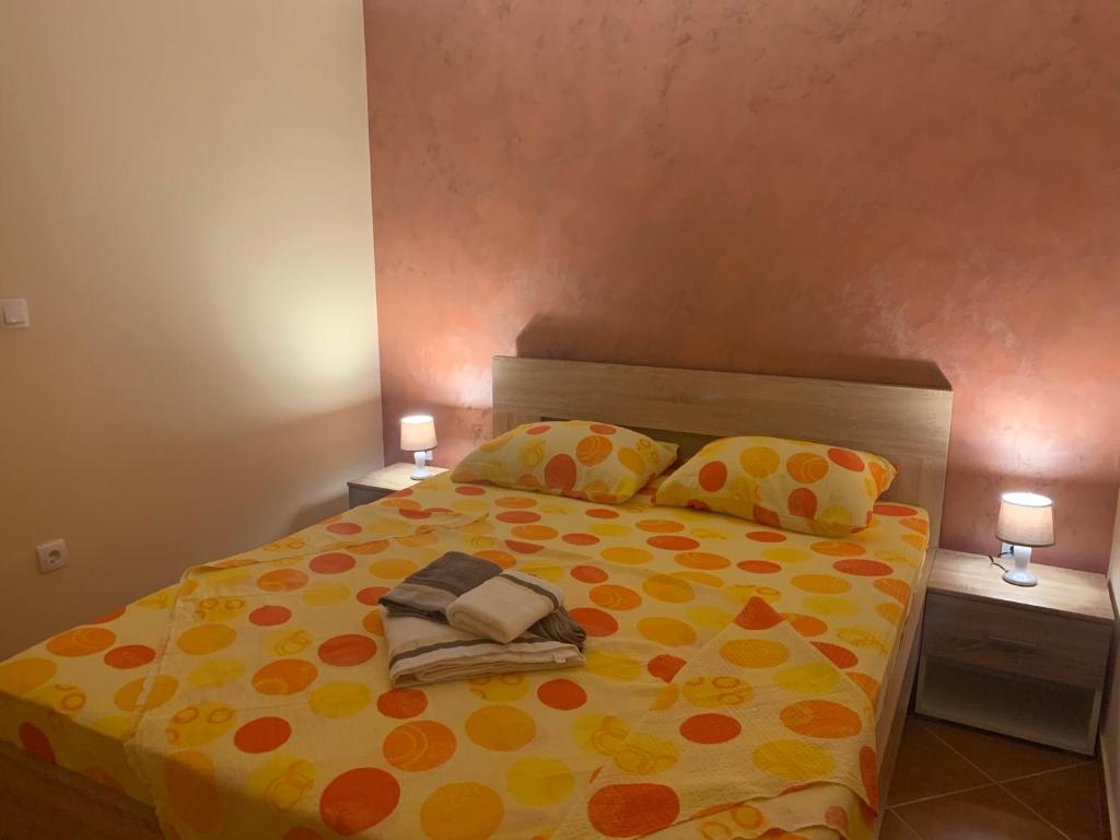 - une chambre avec un lit et une couette jaune et orange dans l'établissement Apartman Joja, à Bar