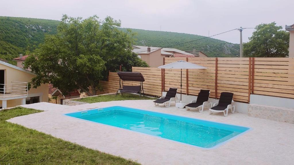 uma piscina com duas cadeiras e um guarda-sol em House for rest Ruda em Grab