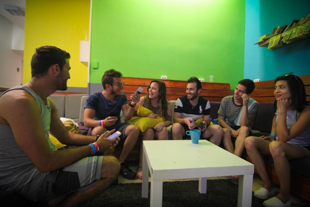 a group of people sitting on a bench playing a video game at Hostel One Budapest in Budapest