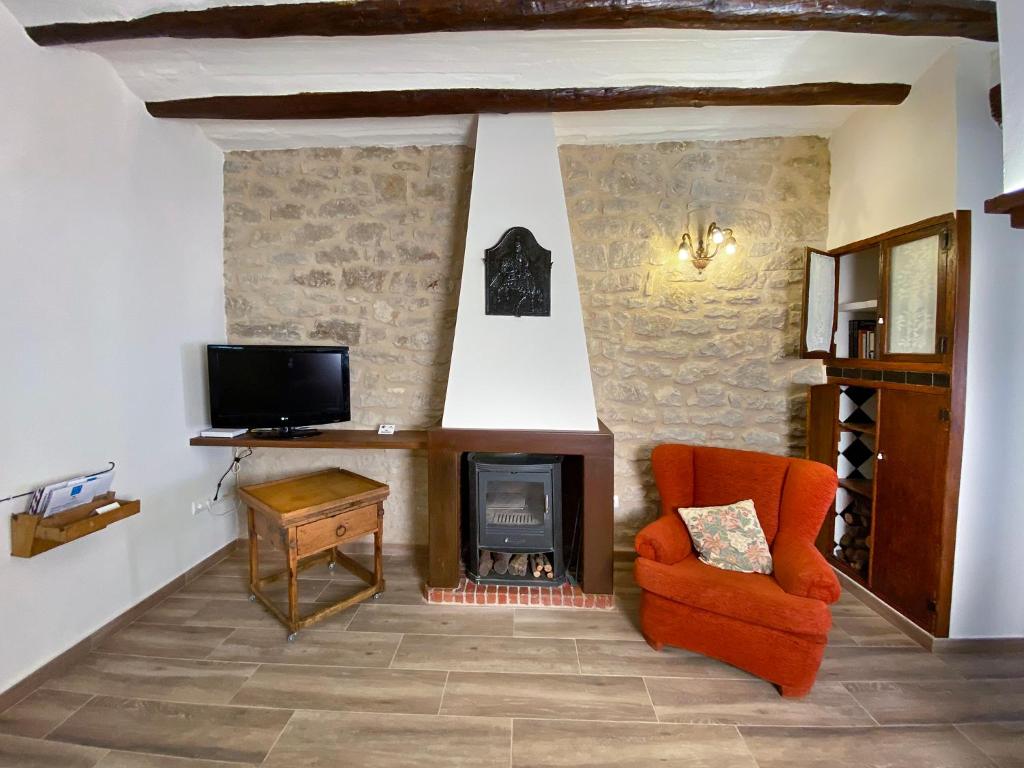 a living room with an orange chair and a fireplace at Casa l'Escorretger in Calaceite