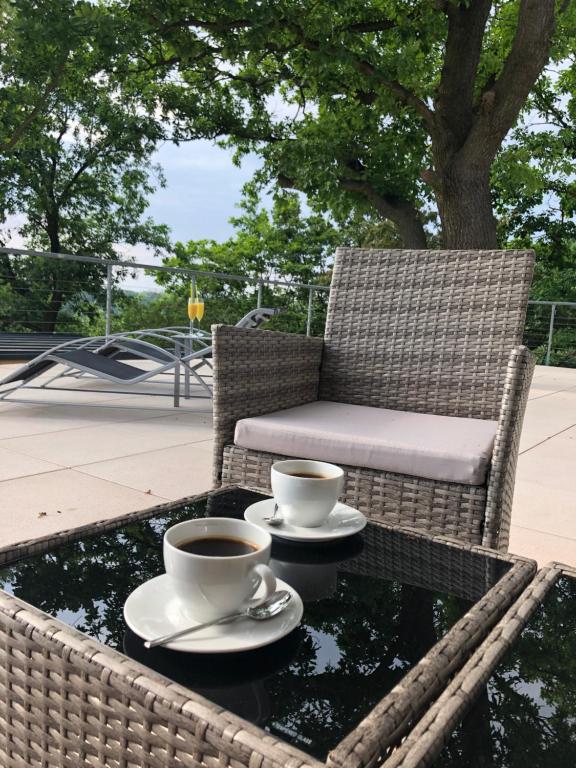 dwie filiżanki kawy na stole z krzesłem w obiekcie Apartmán - D - Vyhlídka nad řekou w mieście Zdiby