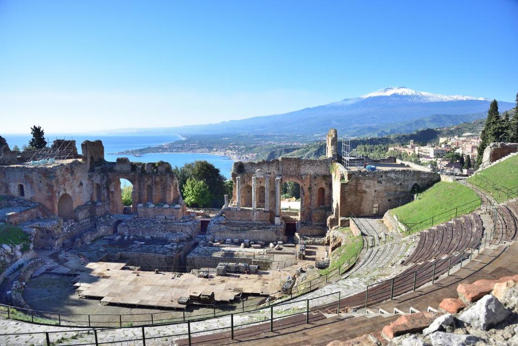 an ancient amphitheater with a lake in the background at B&B Joan's Heritage in Taormina