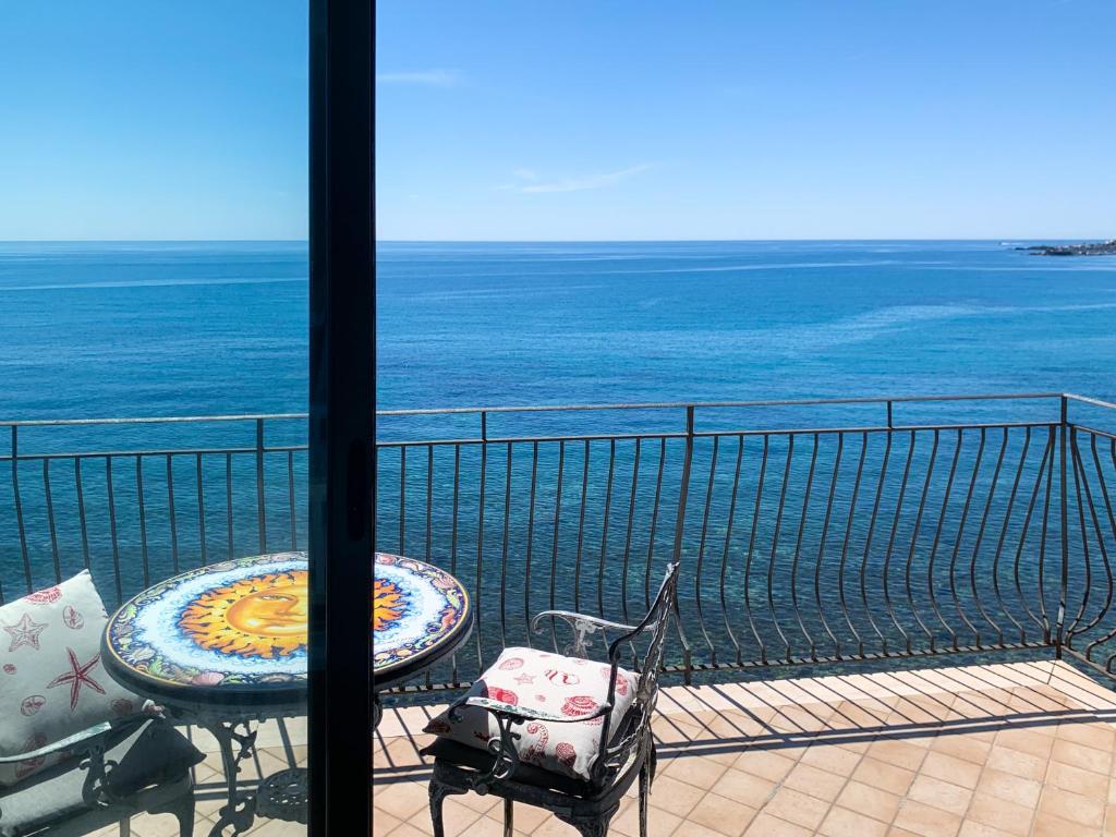 balcón con mesa, sillas y vistas al océano en Giardini Beach loft en Giardini Naxos