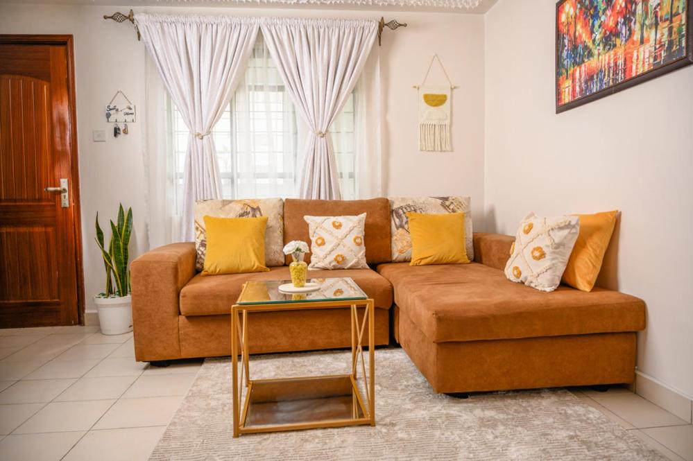 Furnished 1 Bedroom Apartment in Nairobi. 15 Mins to CBD. Free WI-FI & Parking في نيروبي: غرفة معيشة مع أريكة وطاولة