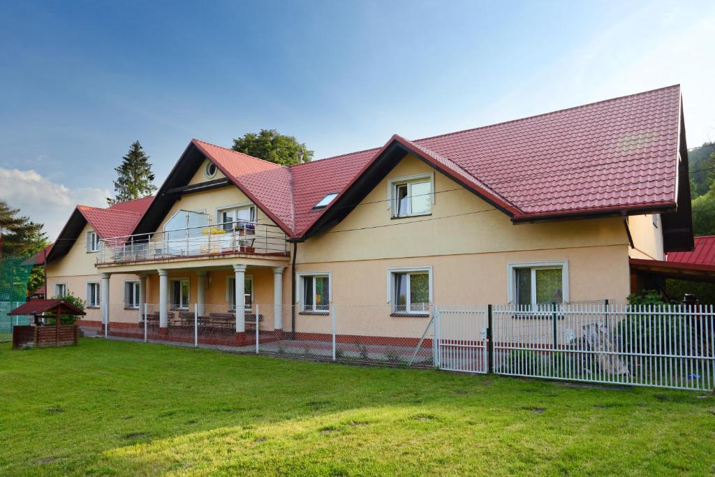 a house with a red roof and a yard at Promenada in Węgierska Górka