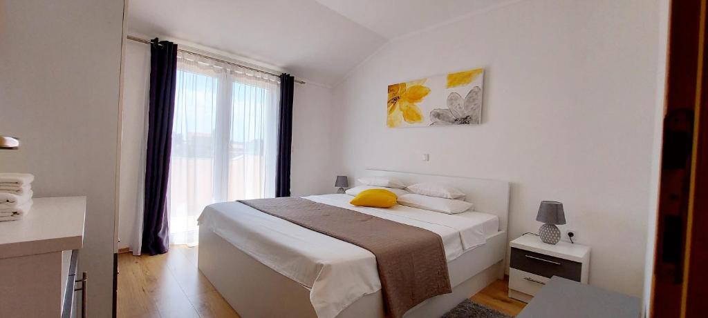a bedroom with a bed with a yellow pillow on it at Apartments Marijana in Rab