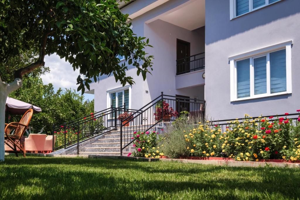 une maison avec des escaliers et des fleurs dans la cour dans l'établissement KAĞAN Holiday Apartments, à Kemer