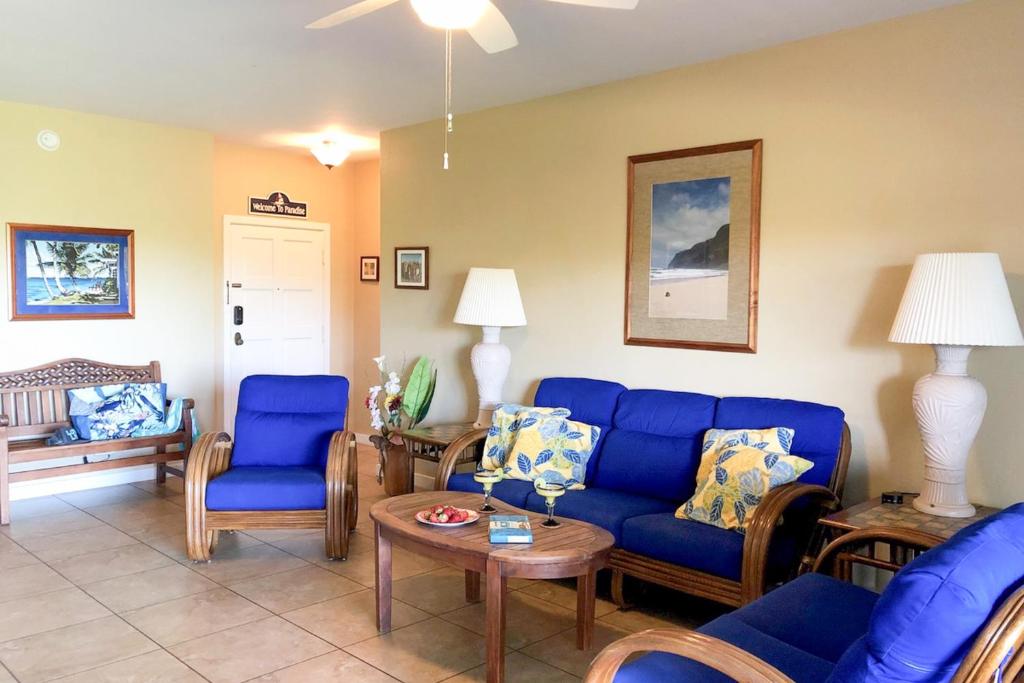 a living room with a blue couch and chairs at Poipu Sands 214 in Kipu