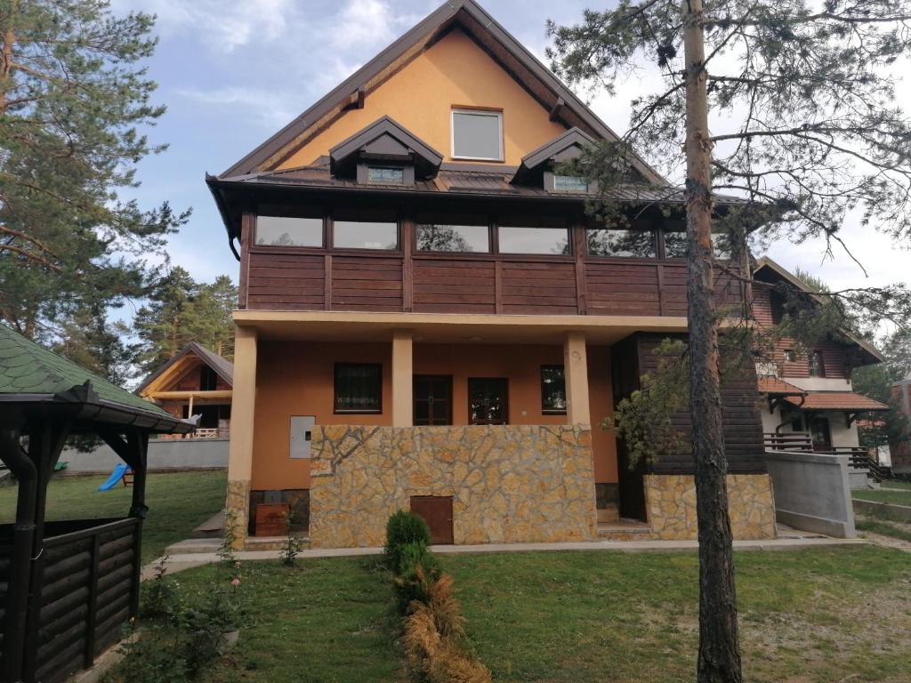 uma casa na floresta com um alpendre à volta em Tara Bozic Apartmani em Kaludjerske Bare