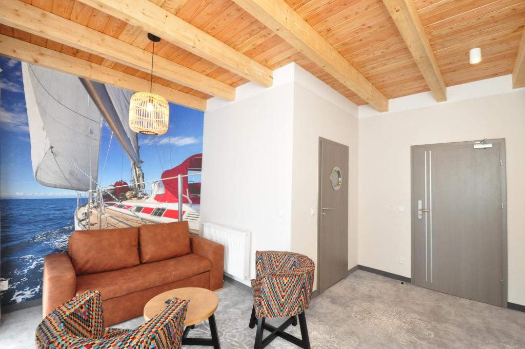 Cozy lounge with sailboat wall mural, brown leather sofa, patterned chairs, wooden-beamed ceiling.