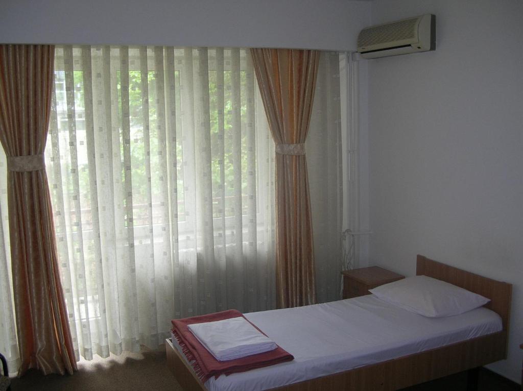 a bedroom with a bed and a window with curtains at Federația Română de Scrimă - Hotel Floreta de Aur in Bucharest