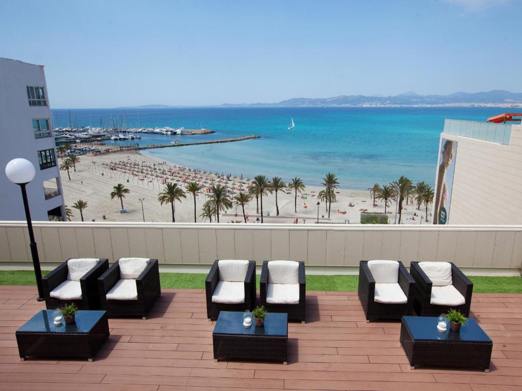 a patio with a view of a beach with chaise lounges at whala!beach in El Arenal