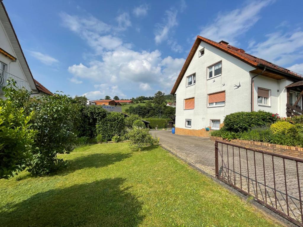 una casa blanca con una valla al lado de un patio en Ferienwohnung Katzenberg, en Bad Soden-Salmunster