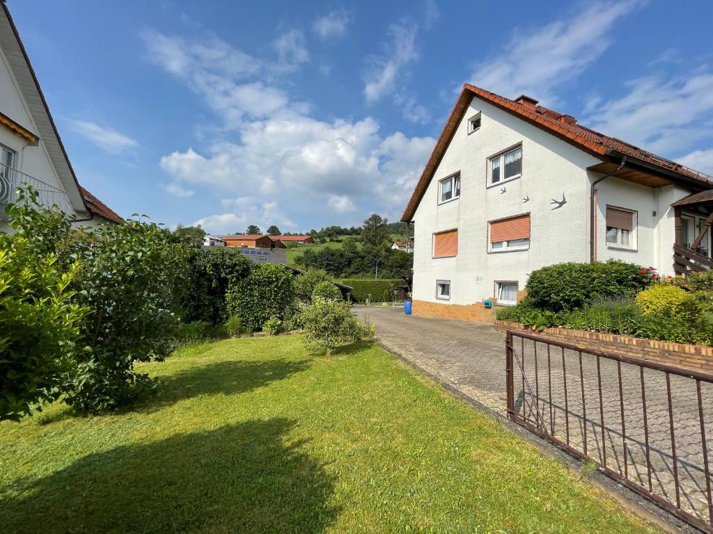 une maison blanche avec une clôture à côté d'une cour dans l'établissement Ferienwohnung Katzenberg, à Bad Soden-Salmünster