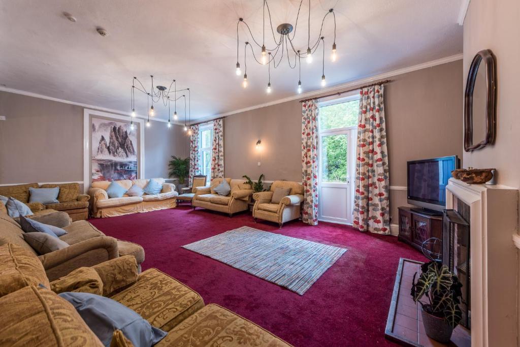 uma sala de estar com um sofá e uma televisão em Private 7 bed wing of former farmhouse, edge of Exmoor, sleeps 16 em East Anstey
