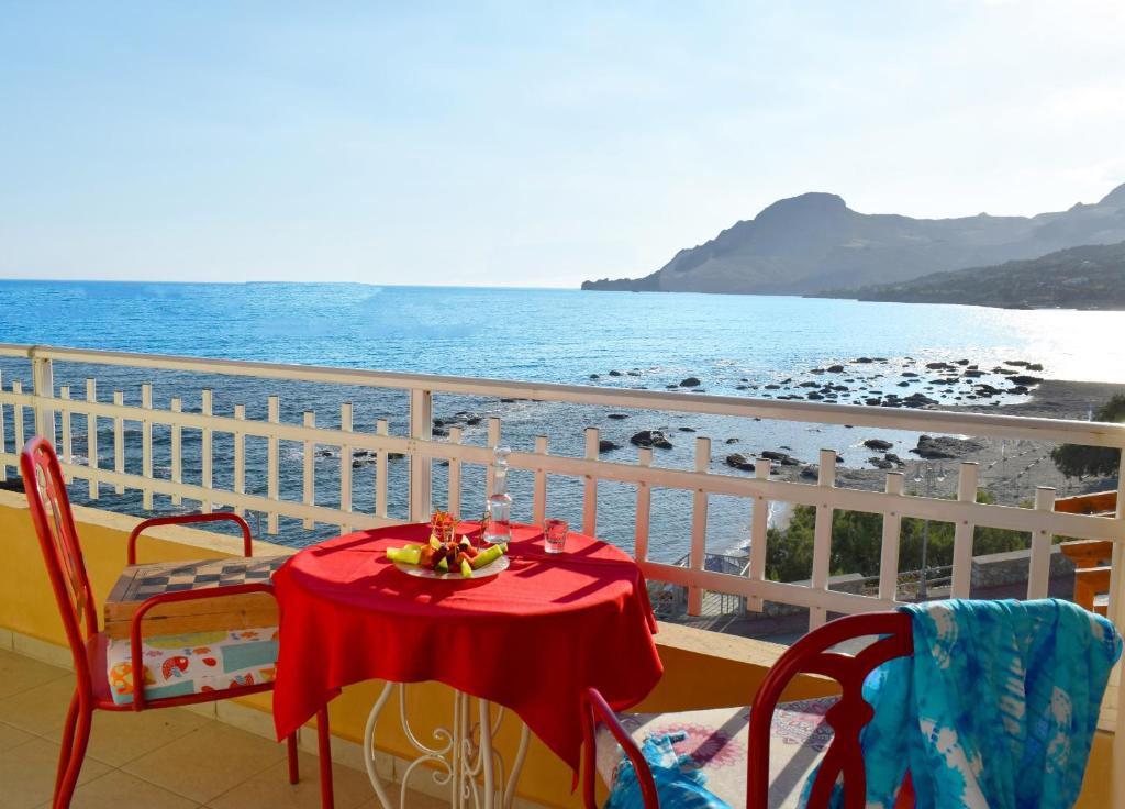 a table on a balcony with a view of the ocean at En Plo Studios & Apartments in Plakias