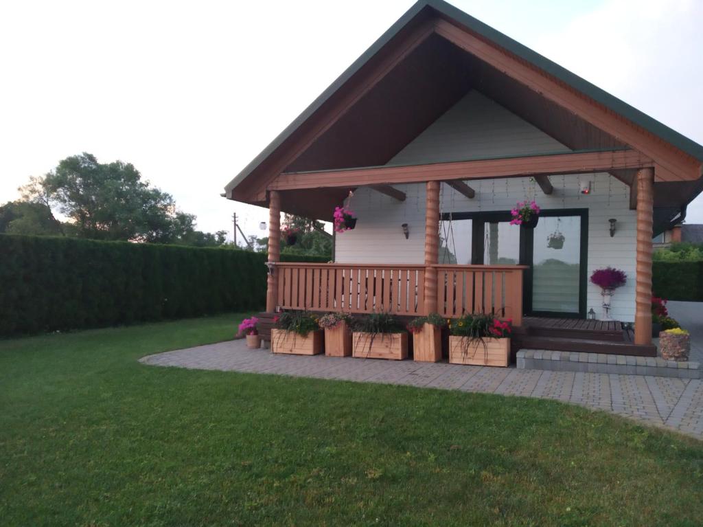 ein kleines weißes Haus mit einer Terrasse mit Blumen in der Unterkunft Pakeliui/On the way in Tauragė