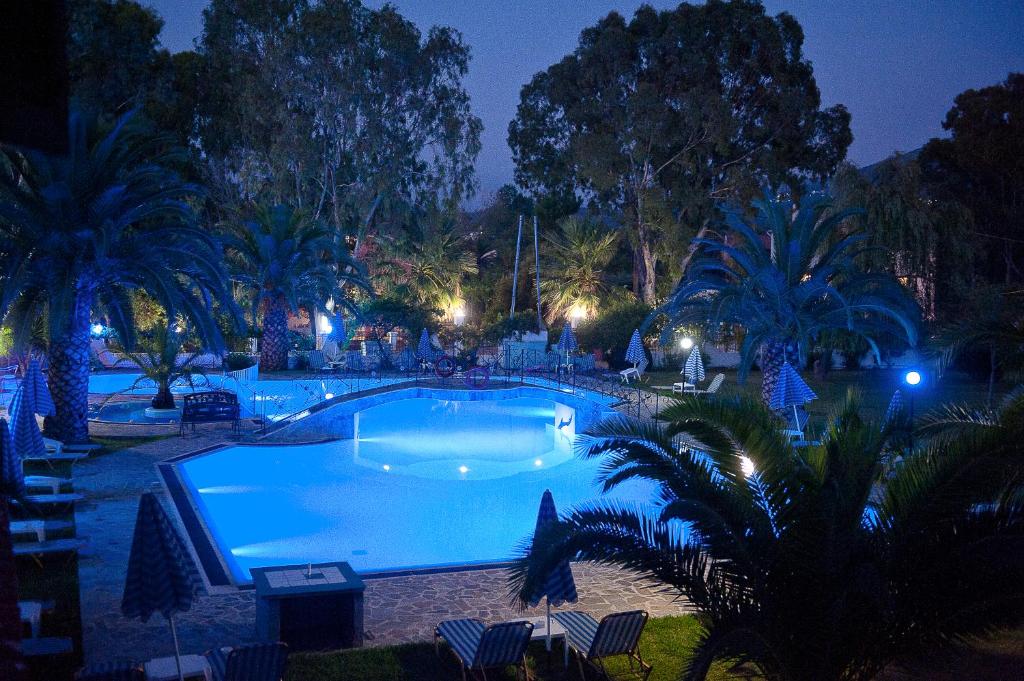 a large swimming pool at night with palm trees at Charlies Venus Apartments in Roda