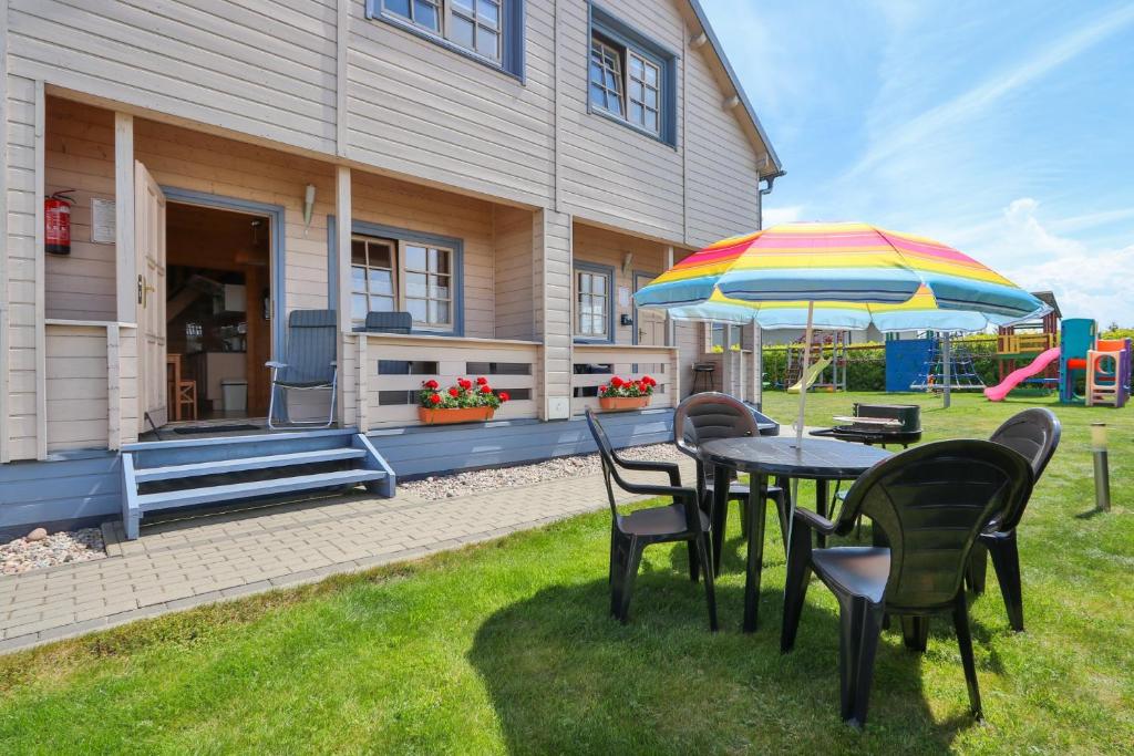 a table and chairs with an umbrella in the yard at Domki Piaskowy Raj in Gąski