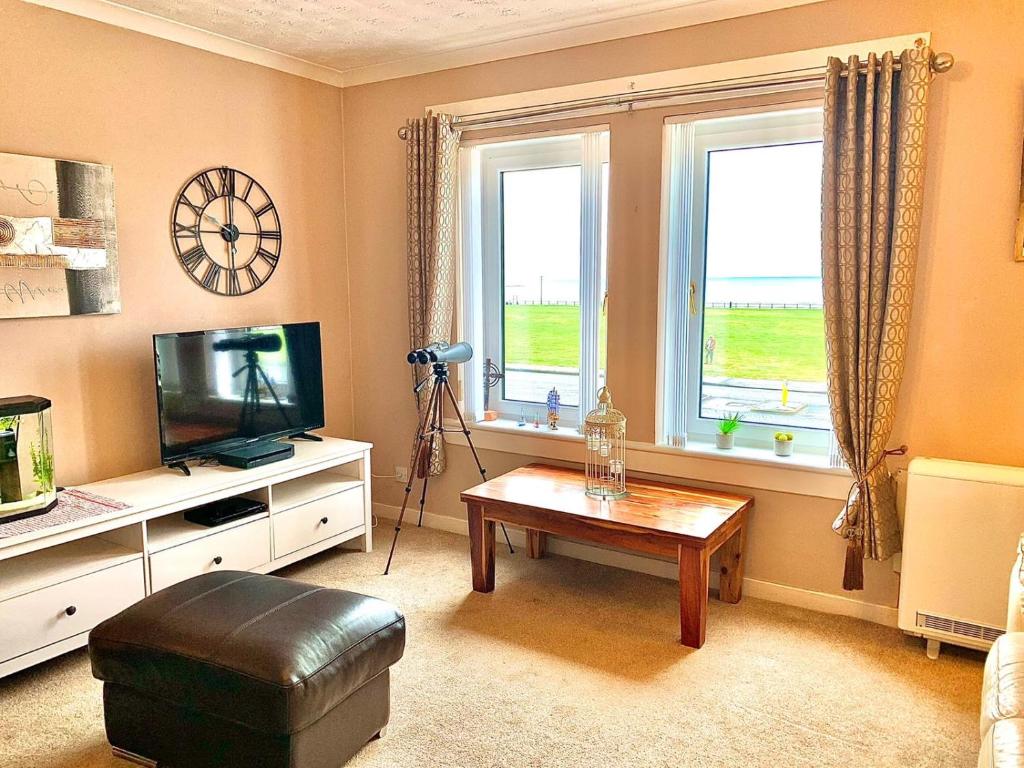 uma sala de estar com uma mesa de centro e uma televisão em Sea View em Ardrossan