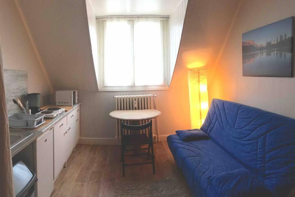 uma sala de estar com um sofá azul e uma mesa em Studio Saint-André em Chambéry